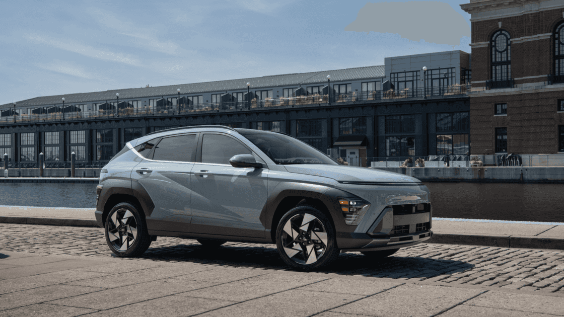 2026 Hyundai Kona gray compact SUV parked by waterfront buildings with side profile view.