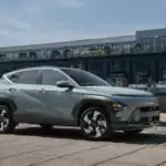 2027 Hyundai Kona gray compact SUV parked by waterfront with side profile and modern wheel design.