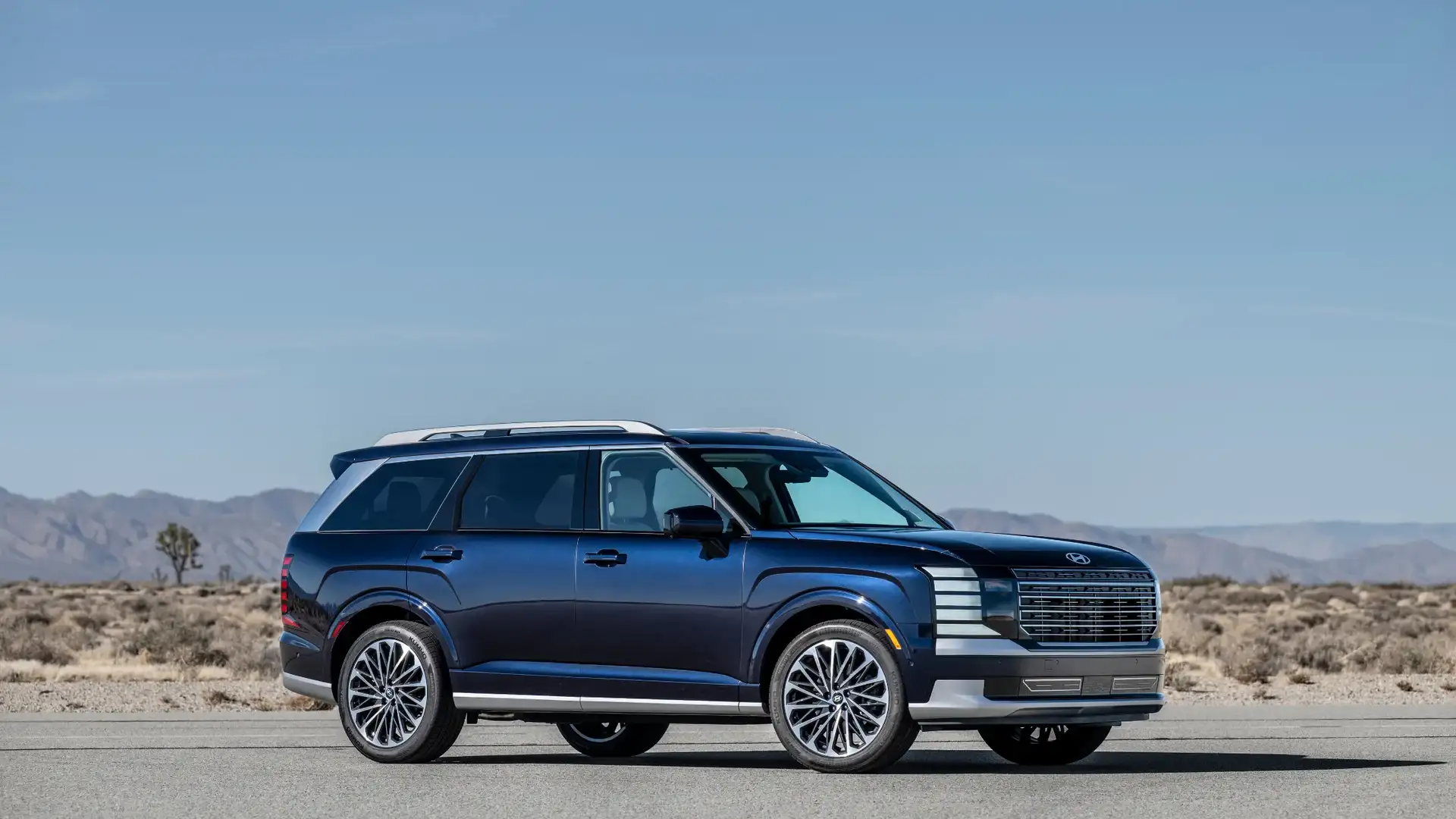 2027 Hyundai Palisade blue SUV shown in side profile on desert road with mountain backdrop.