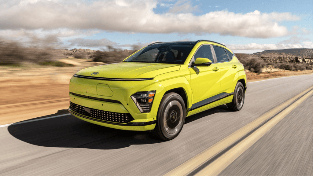 Front-side view of the 2025 Hyundai Kona Electric in vibrant green driving on a desert highway.
