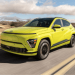 Front-side view of the 2025 Hyundai Kona Electric in vibrant green driving on a desert highway.