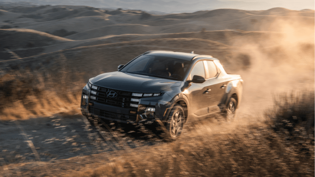 2025 Hyundai Santa Cruz kicking up dust on an off-road trail through dry rolling hills at sunset.