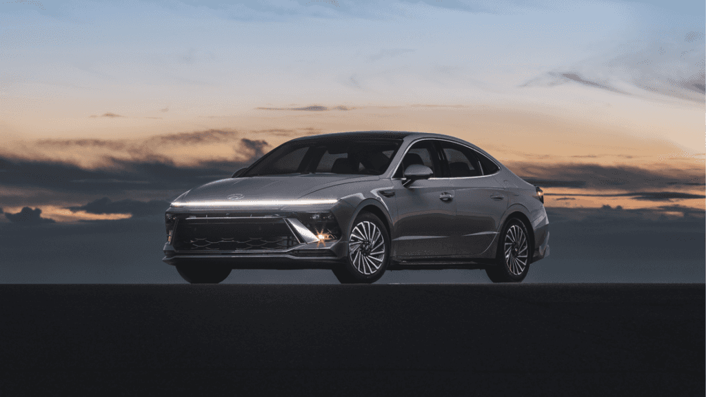 Side view of the 2025 Hyundai Sonata Hybrid parked at dusk with LED lights on and a dramatic sky.
