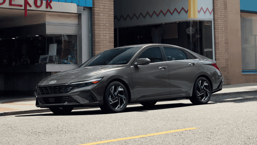 2025 Hyundai Elantra Hybrid in gray parked on city street outside storefronts.