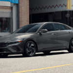 2025 Hyundai Elantra Hybrid in gray parked on city street outside storefronts.