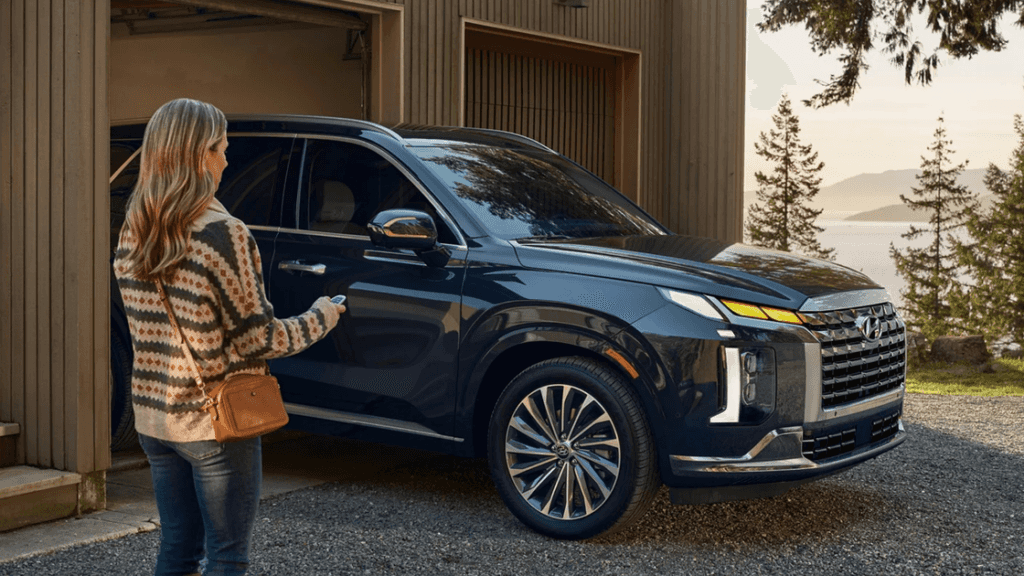 2025 Hyundai Palisade in black parked outside a home with woman approaching using key fob.