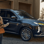 2025 Hyundai Palisade in black parked outside a home with woman approaching using key fob.