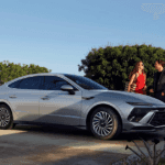 2025 Hyundai Sonata in silver parked in a modern driveway with couple standing nearby.