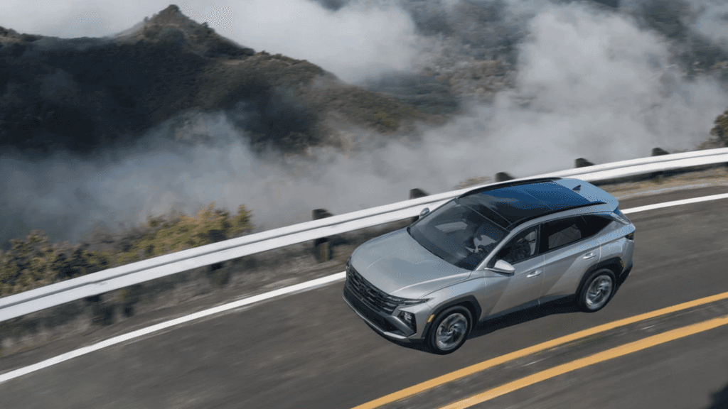 Aerial view of the 2025 Hyundai Tucson Plug-in Hybrid in silver driving along a mountain road.