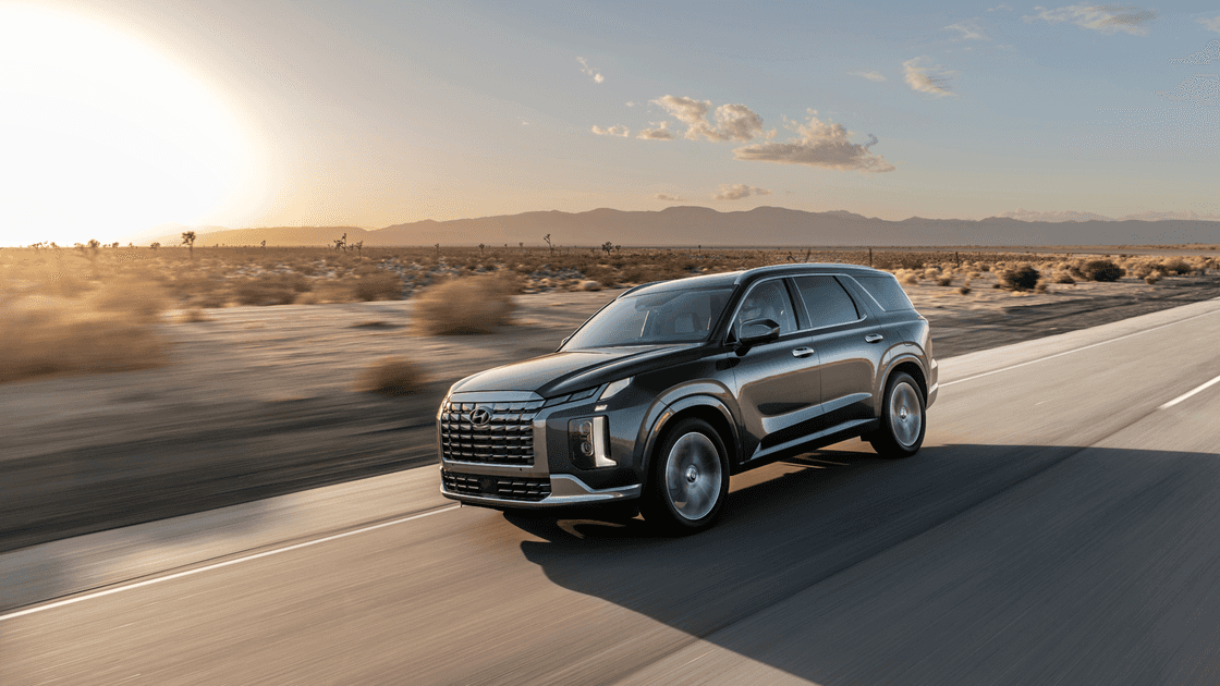 2025 Hyundai Palisade driving at sunset on desert highway with chrome grille and LED headlights.