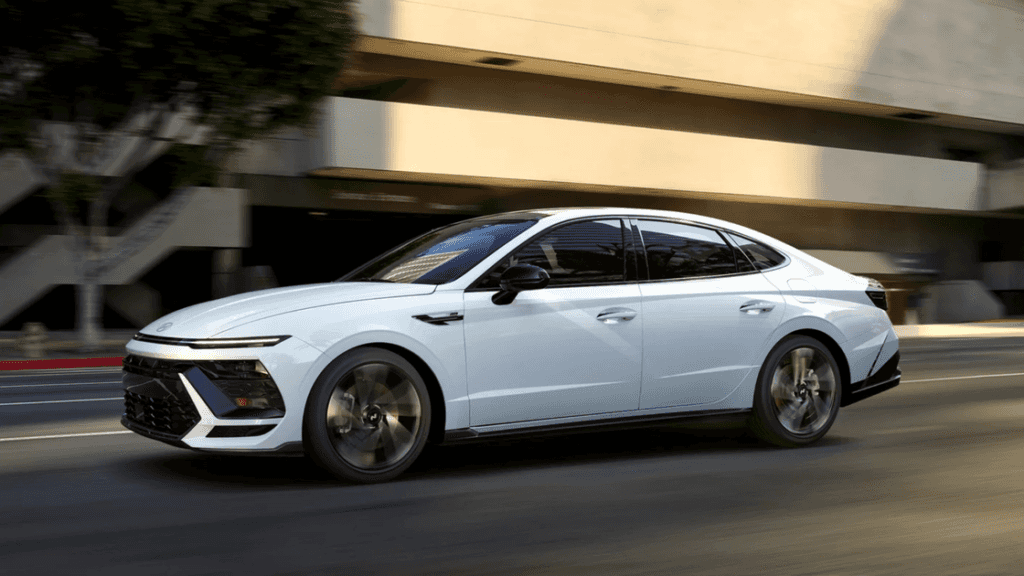 2025 Hyundai Sonata in white driving through city street with modern blacked-out roof.