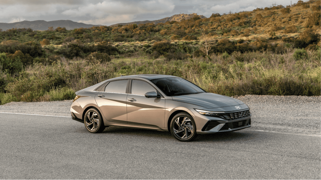 Front-side view of a gray 2025 Hyundai Elantra sedan parked on a scenic roadside.
