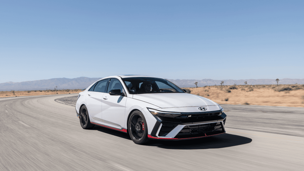 2025 Hyundai Elantra N in white driving on a desert road with black wheels and red accents.