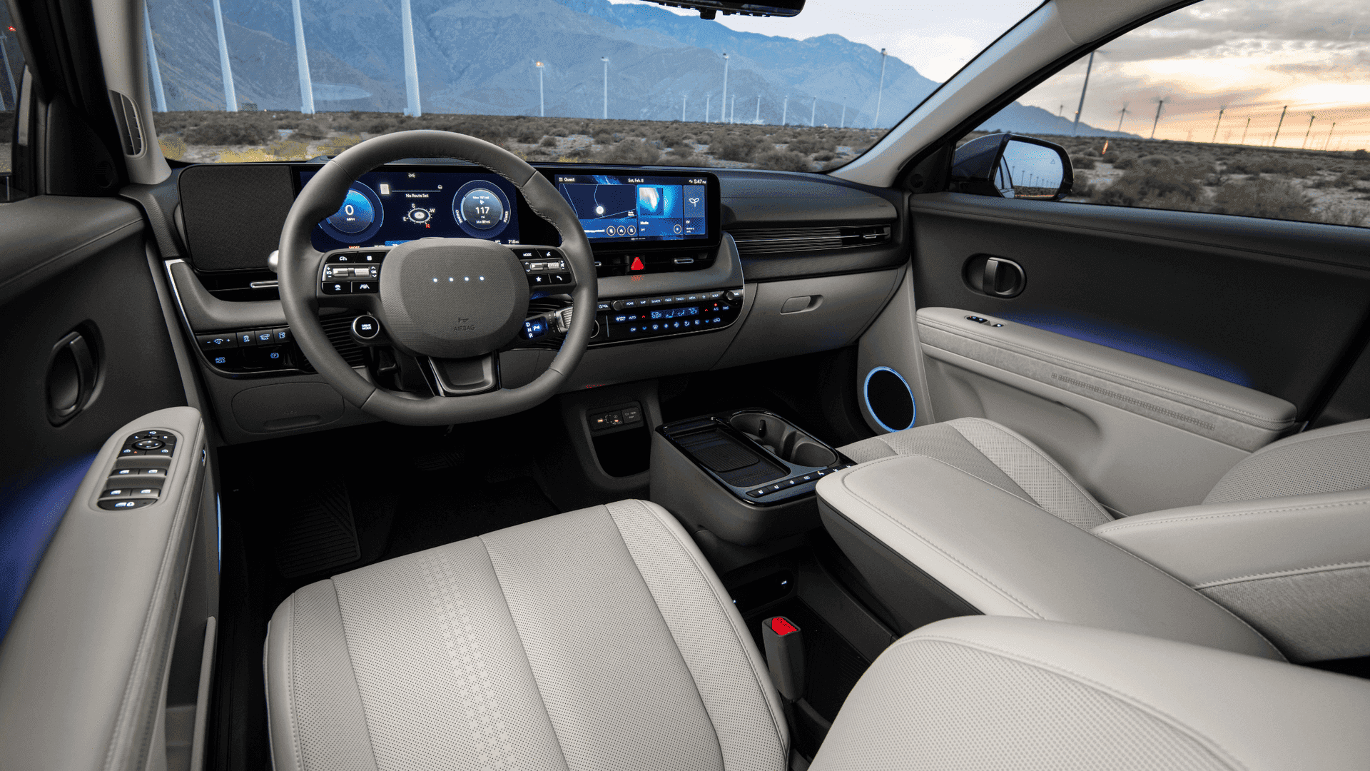 Driver's view of 2025 Hyundai IONIQ 5 cabin with dual displays and ambient lighting at dusk.