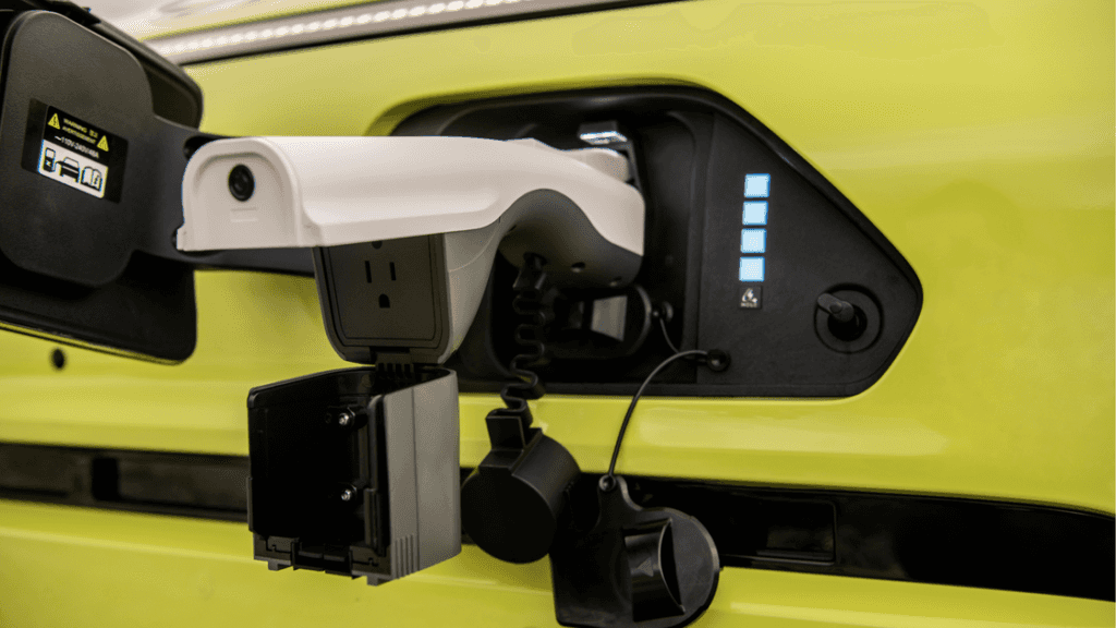 2025 Hyundai Kona Electric charging port with connected plug and illuminated battery level indicator.