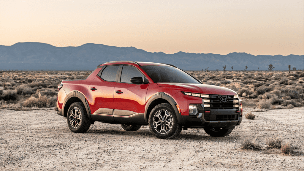 2025 Hyundai Santa Cruz in red shown parked on desert terrain at sunset with rugged front design.