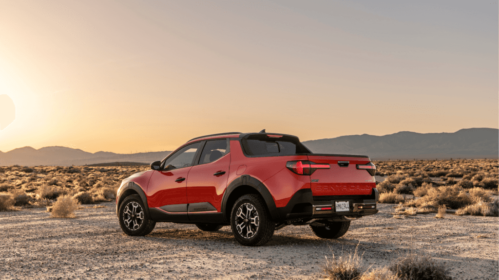 Rear view of the 2025 Hyundai Santa Cruz in red with bold tailgate design and off-road backdrop.