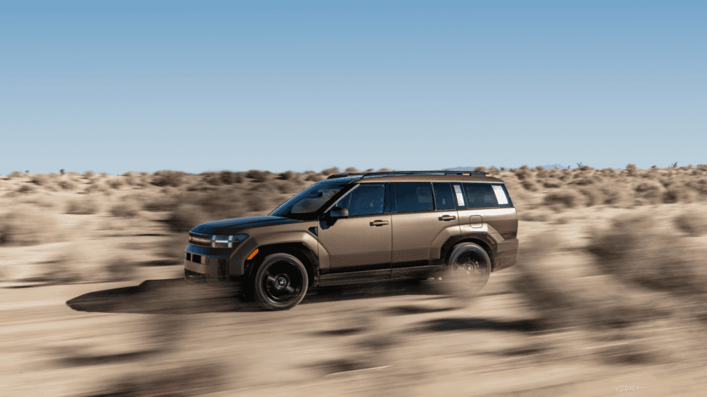 2025 Hyundai Santa Fe in bronze driving through desert terrain at speed.