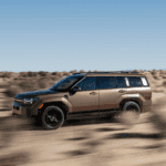 2025 Hyundai Santa Fe in bronze driving through desert terrain at speed.