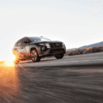2025 Hyundai Tucson SUV driving at sunset on a desert highway with lens flare effect.