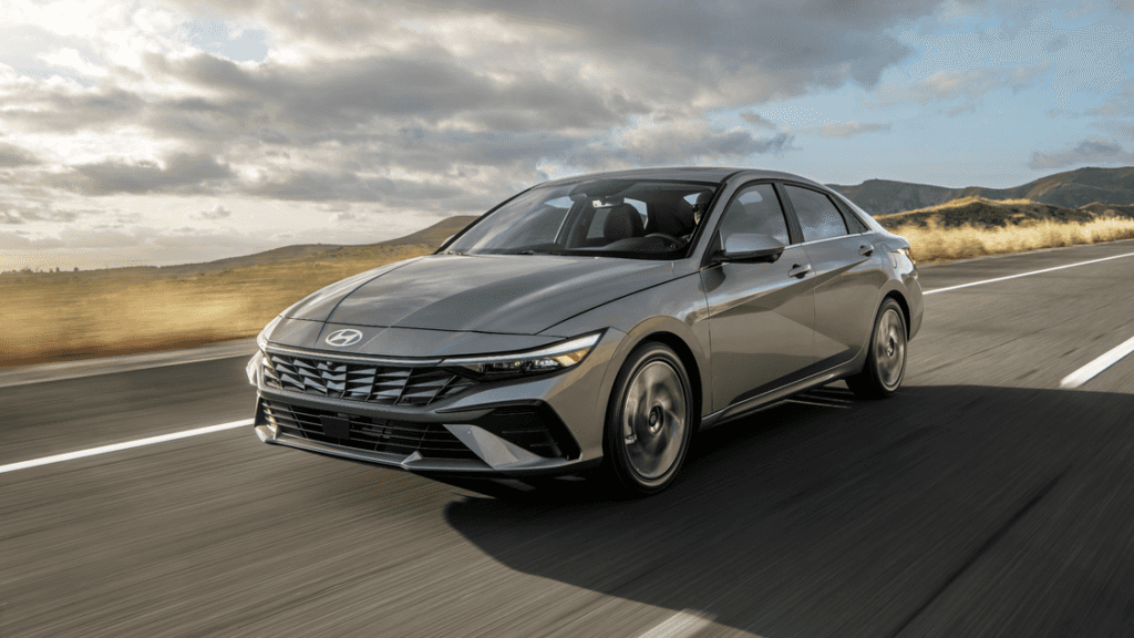 2025 Hyundai Elantra sedan driving on highway with sleek front-end design and silver finish.