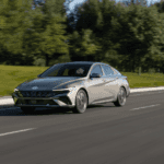 2025 Hyundai Elantra compact sedan in silver driving on suburban road with modern front-end styling.