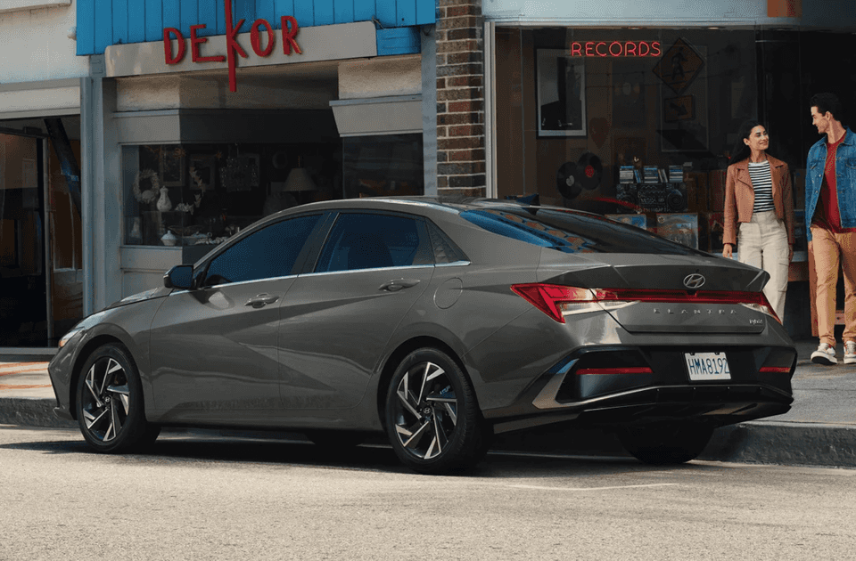 Rear view of the 2025 Hyundai Elantra Hybrid parked on city street near a record.
