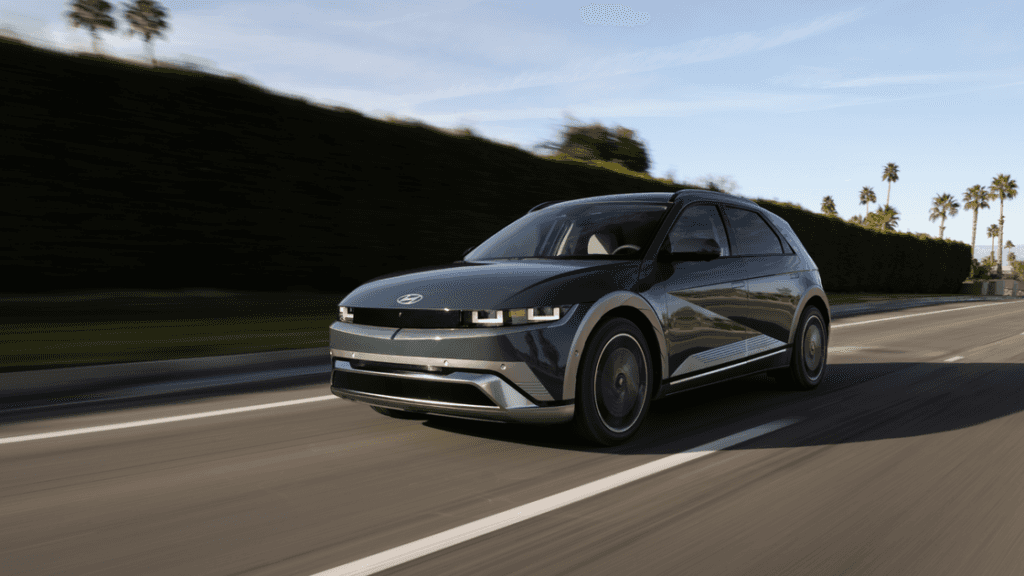 2025 Hyundai IONIQ 5 in motion on a palm-lined road, showcasing its modern EV design and LED lighting.