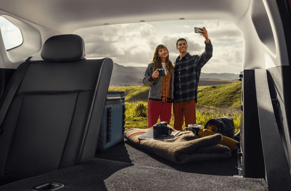 View from rear cargo area of 2025 Hyundai Kona with seats folded and couple standing outside.