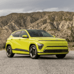 Lime green 2025 Hyundai Kona Electric parked in front of desert mountains under overcast skies.