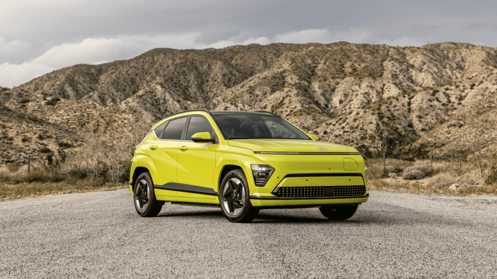 Lime green 2025 Hyundai Kona Electric parked in front of desert mountains under overcast skies.
