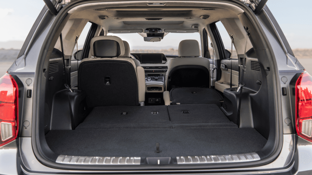 2025 Hyundai Palisade driving on a desert road with mountains in the background.