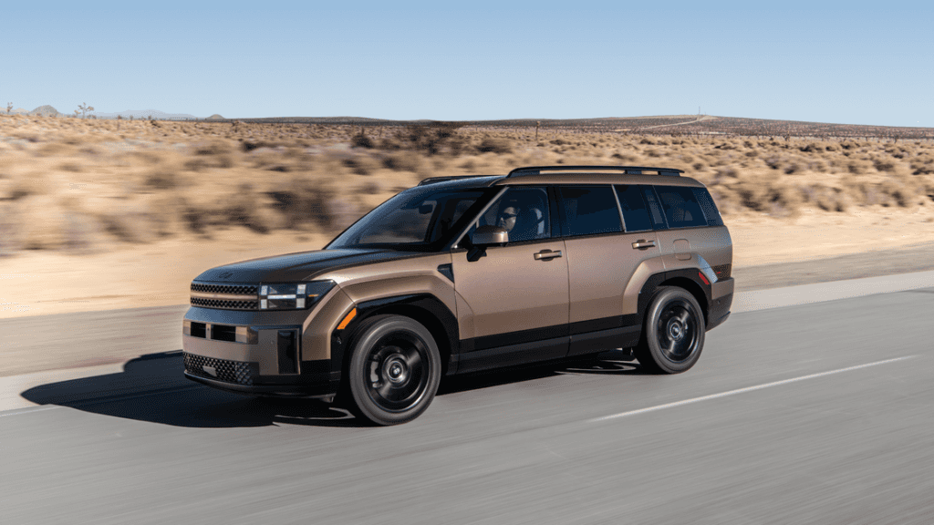 2025 Hyundai Santa Fe Hybrid driving on desert road showcasing its rugged, modern exterior design.