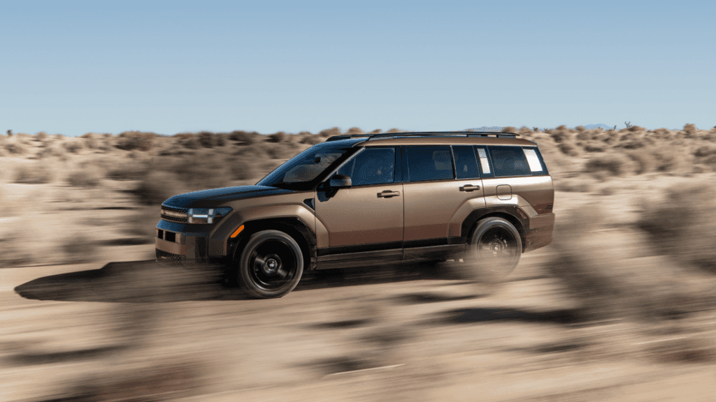 2025 Hyundai Santa Fe Hybrid driving off-road in desert terrain with bold exterior and rugged stance.