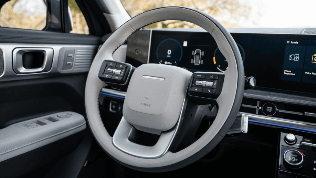 Close-up of 2025 Hyundai Santa Fe steering wheel with dual-screen digital display and control buttons.