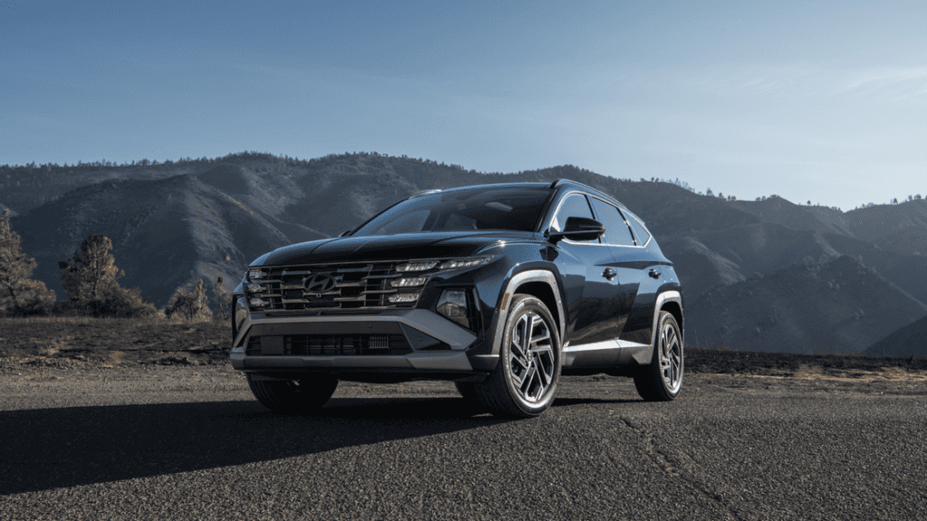 Front view of the 2025 Hyundai Tucson Hybrid parked near a mountain range with daytime running lights on.