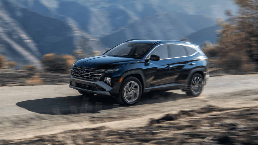 2025 Hyundai Tucson Hybrid in motion on mountain road showcasing bold front grille and sleek design.