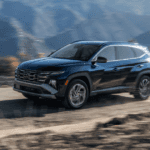 2025 Hyundai Tucson Hybrid in motion on mountain road showcasing bold front grille and sleek design.