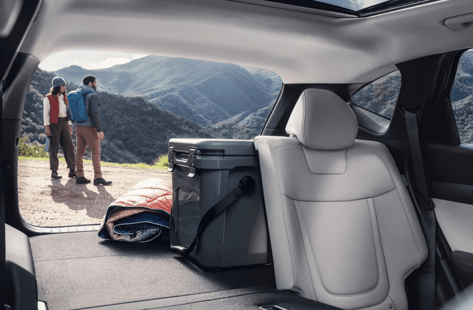 2025 Hyundai Tucson Plug-in Hybrid rear cargo view with folded seats, cooler, and outdoor gear.