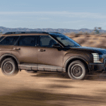 2026 Hyundai Palisade driving off-road in desert terrain with rugged styling and bold side profile.