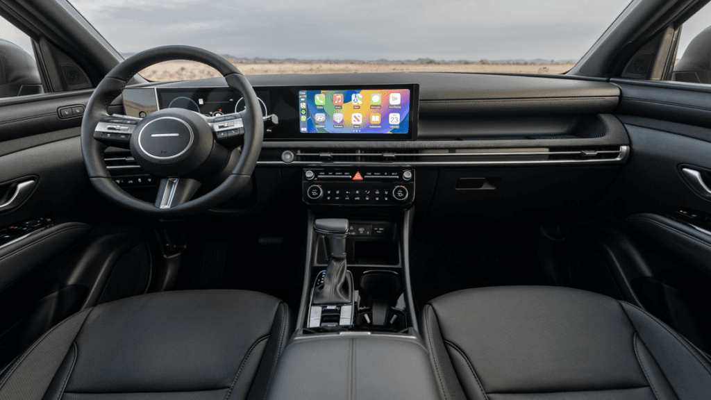 2025 Hyundai Santa Cruz front interior featuring black leather seats and panoramic touchscreen display.