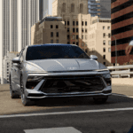Front view of a silver 2025 Hyundai Sonata Hybrid stopped at a city crosswalk with pedestrians passing.