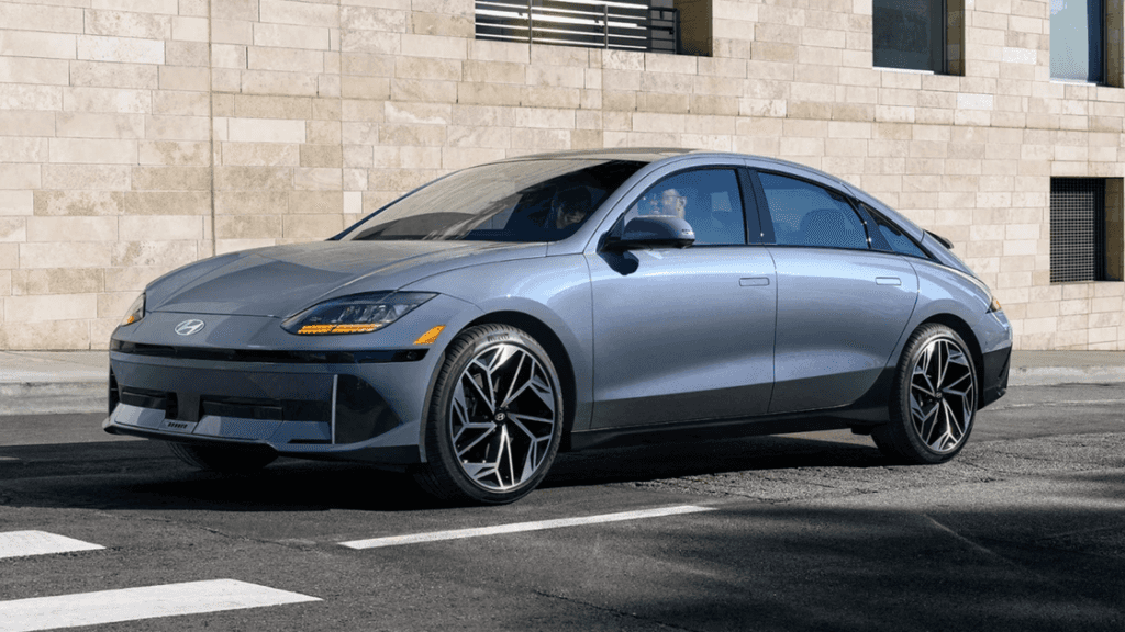 2025 Hyundai IONIQ 6 in metallic gray with aerodynamic body design and black alloy wheels parked near a stone building.