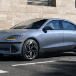 2025 Hyundai IONIQ 6 in metallic gray with aerodynamic body design and black alloy wheels parked near a stone building.