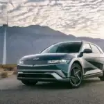 2026 Hyundai IONIQ 5 electric SUV parked near wind turbines with mountain scenery in background.