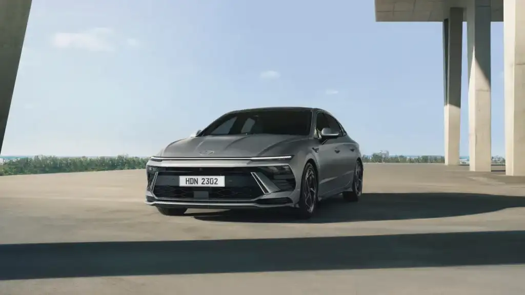 2026 Hyundai Sonata sedan in matte gray parked under modern structure with bold front design.