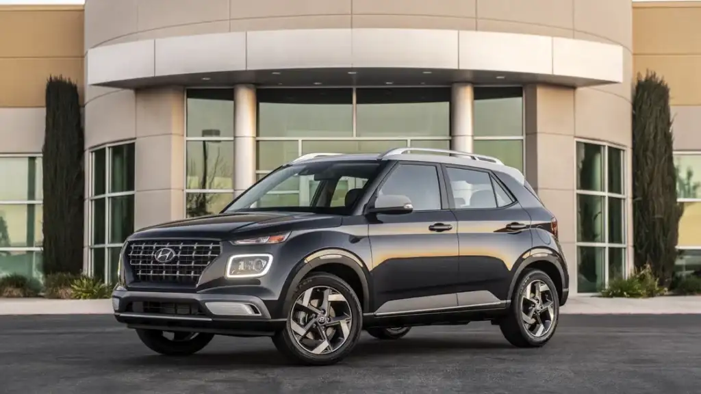 2026 Hyundai Venue compact SUV in dark gray parked in front of modern building with bold grille.