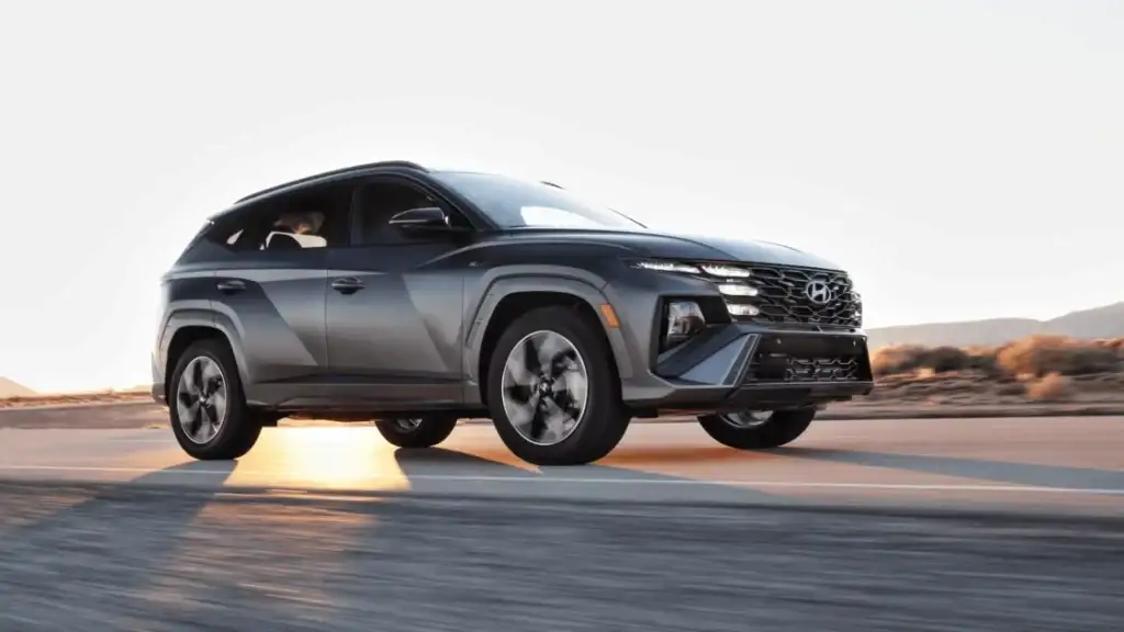 Matte gray 2025 Hyundai Tucson SUV in motion on a desert highway, captured during golden hour lighting.