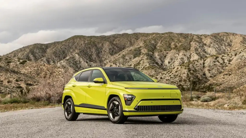 Bright lime exterior of 2026 Hyundai Kona Electric parked on road with mountain landscape view.