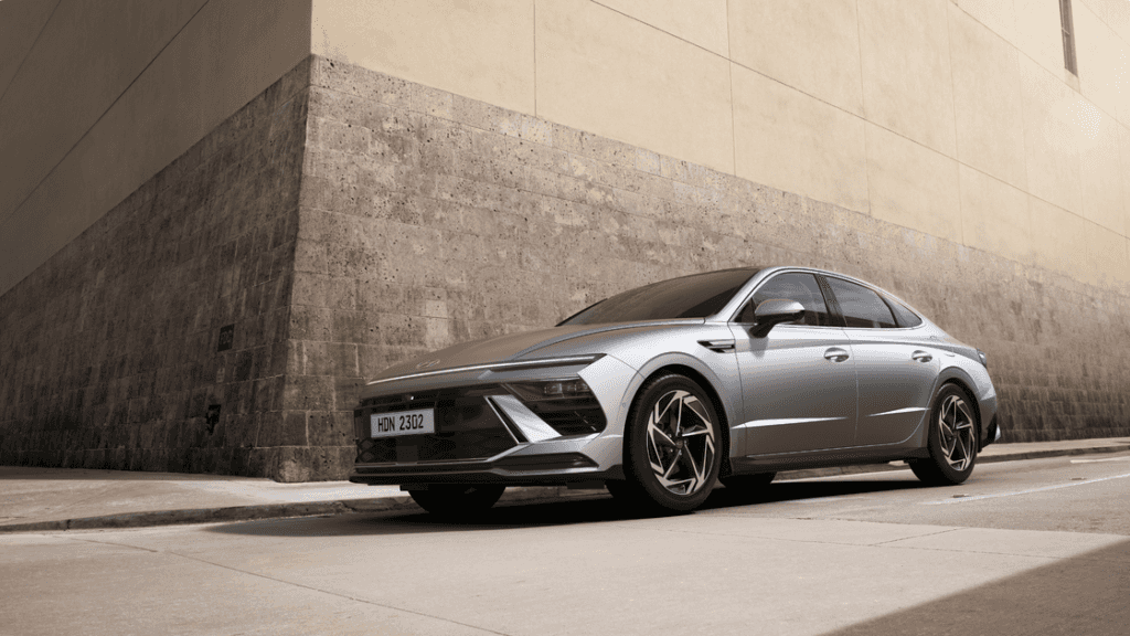 2025 Hyundai Sonata parked by tall wall showcasing sleek silver exterior and sharp front design.